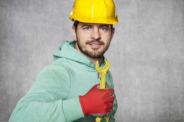 Smiling Worker Holding A Yellow Wrench
